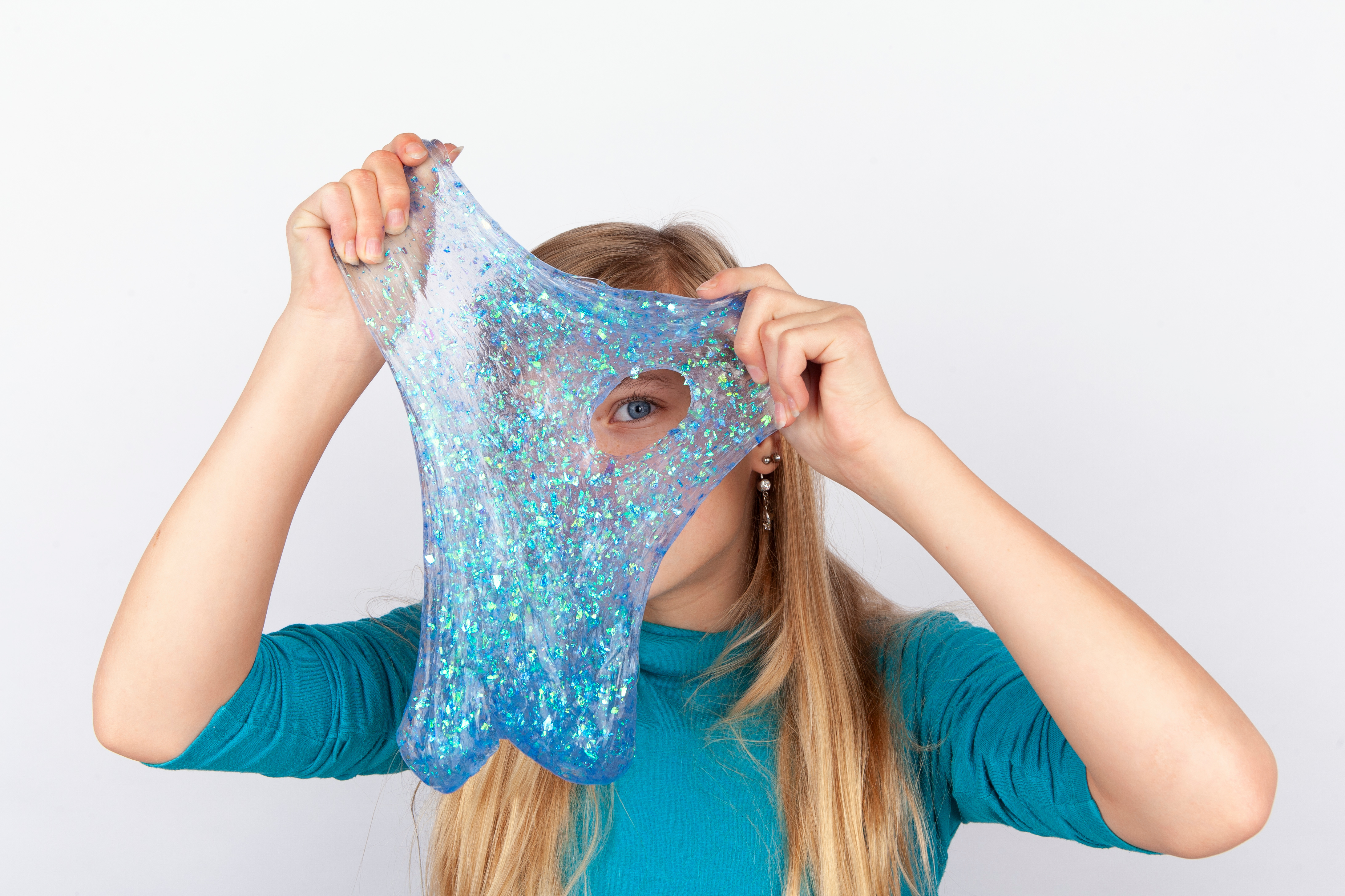 A girl in blue peaking through a hole in the slime she is playing with